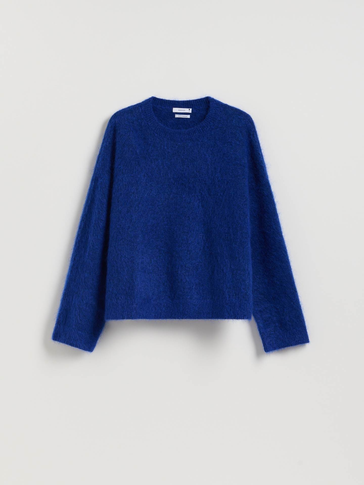 Reserved plavi četkani džemper na beloj pozadini.