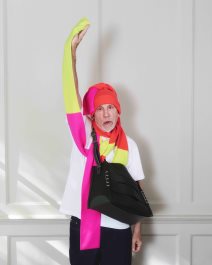 Glumac John Malkovich sa šarenim šalom, crvenom kapom i crnom torbom.