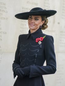 Kate Middleton u crnom coatdressu, šeširom iste nijanse i punđom sa strane.