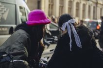 Dve devojke okrenute leđima: jedna nosi krznenu kapu, druga mašnu u kosi.