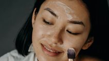 Žena četkicom nanosi masku na lice.