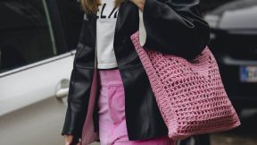Žena u roze somotskim pantalonama, ružičastoj torbi i crnoj kožnoj jakni.