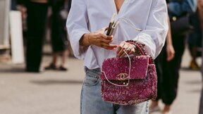 Krupan kadar na roze Chanel torbu koju nosi žena u beloj košulji i farmerkama.