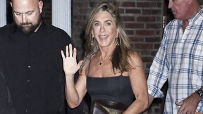 Jennifer Aniston u sivoj haljini sa braon torbom.