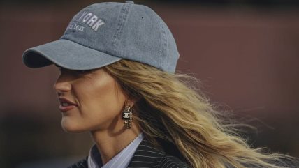 Žena sa plavom kosi nosi sivi kačket sa natpisom New York.