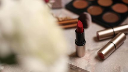 Krupan kadar na sto sa šminkom i crvenim karminom.