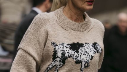 Žena u krem džemperu na kom je nacrtan pas.