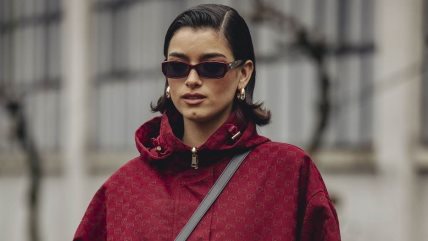 Žena u crvenoj šuškavoj jakni sa crnom torbicom.