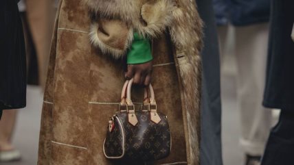 Žena u krznenom kaputu držni malu torbicu.