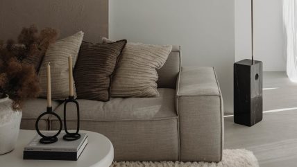 Deo dnevnog boravka na kome se vidi kauč sa jastucima i stočić na kome su knjige i sveće.