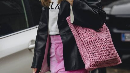 Žena u roze somotskim pantalonama, ružičastoj torbi i crnoj kožnoj jakni.