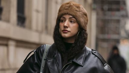 Žena u crnoj kožnoj jakni i rolci iste nijanse, sa krznenom šubarom na glavi.