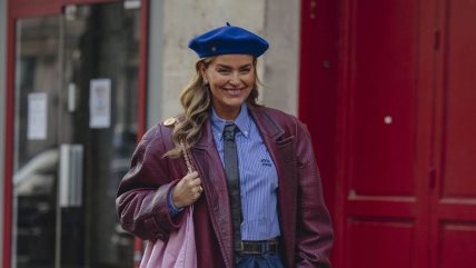 Žena u plavoj košlji i bordo kaputu, sa plavom beretkom i crnom kravatom.