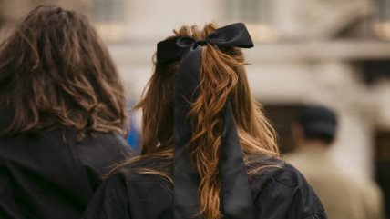 Krupan kadar na ženu obučenu u crno, sa bakarnom bojom kose koja je uvijena u talase i zakačena crnom mašnom.