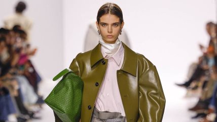 Manekenka u khaki kožnom mantilu preko roze košulje, sa zelenom torbom na Bottega Veneta reviji.