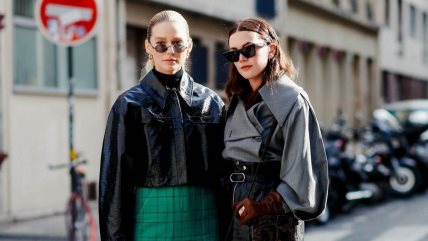 Dve žene stoje jedna pored druge. Jedna je u zelenoj suknju i puf crnoj jakni, druga je u crnoj suknji i sivoj puf jakni.