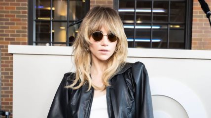 Suki Waterhouse sa francuskim šiškama u beloj majici, kožnoj jakni, naočarima.