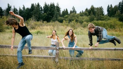 grupa prijatelja preskače ogradu u prirodi