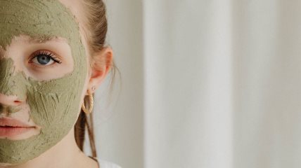 Krupan kadar žene koja ima zelenu masku od gline za lice.