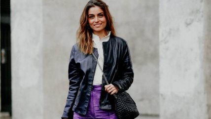 Žena u ljubičastim pantalonama od pliša, beloj košulji i kožnoj jakni.