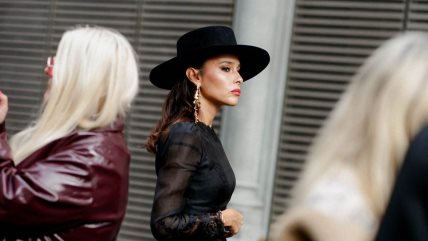 Devojka u crnoj haljini, sa šeširom u istoj nijansi i efektnim minđušama.