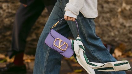 Žena nosi malu ljubičastu torbu.