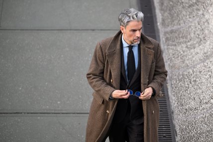 Muškarac u braon kaputu i tamnom odelu na Pitti Uomo 109.