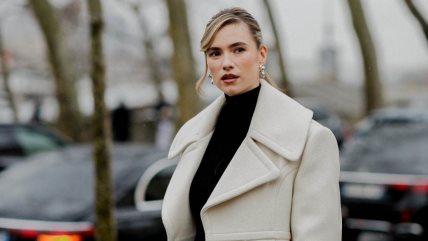 Žena u belom oversized kaputu ispod kog je crna rolka.