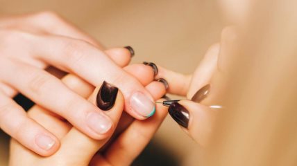 Žena drži ruku druge žene dok joj pažljivo sređuje nokte tokom tretmana manikira.