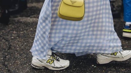 Krupan kadar na New Balance patike stilizovane sa plavom suknjom i žutim torbicom.