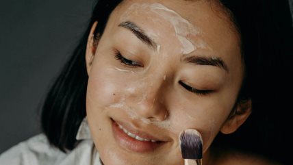 Žena četkicom nanosi masku na lice.