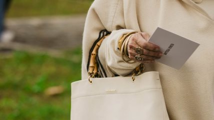 Žena u belom stajlingu nosi bucket bag u istoj boji.
