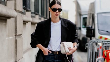 Devojka u tamnim farmerkama, baloj majici i crnom  blejzeru.