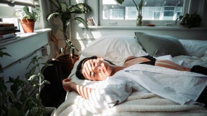 Žena leži na krevetu.