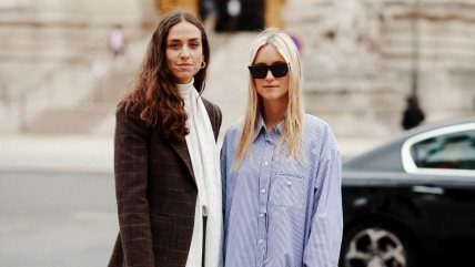 Dve devojke stoje na ulici; jedna je u plavoj košulji, druga je u braon sakou.