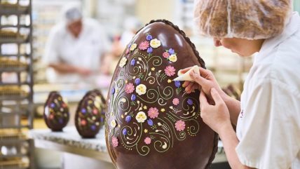 Žena ukrašava veliko čokoladno uskršnje jaje.