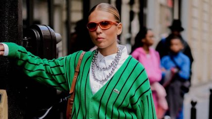 Devojka u beloj košulji i zelenom džemperu.