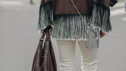 Žena u belim pantalonama i jaknom sa resama.