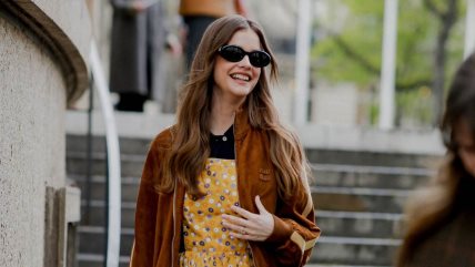 Devojka u žutoj haljini i braon kožnoj jakni.