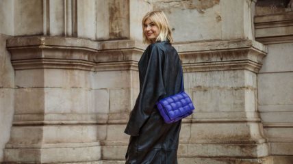 Devojka u crnoj kombinaciji sa plavom pletenom torbom od kože.