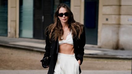 Devojka u belim pantalonama, topu i crnoj jakni.