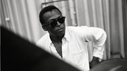 Miles Davis u beloj košulji i sa crnim naočarima za sunce.