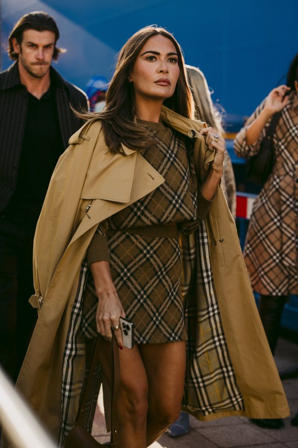 Žena u kariranom kompletu i krem mantilu