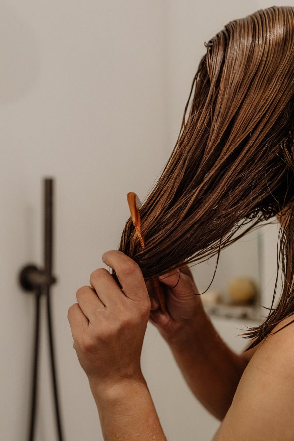 Žena češlja mokru kosu.