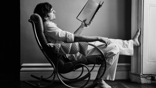 Glumac Jacob Elordi sedi na stolici sa jednom ispruženom nogom i čita knjigu za potrebe nove Bottega Veneta kampanje