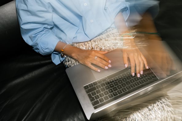 Žena sedi i drži laptop.