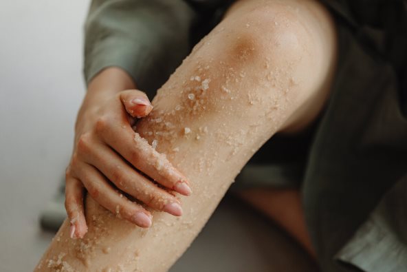 Žena nanosi piling na kožu.