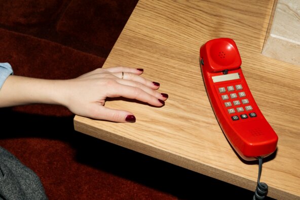 kaboompics_hand-resting-near-retro-red-telephone-on-table-42554.jpg